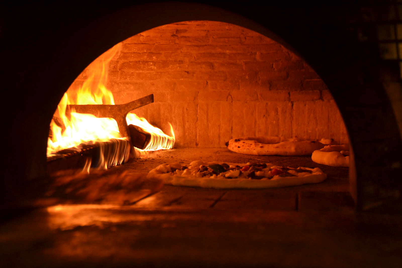 Pizze in cottura nel forno a legna acceso di Josè