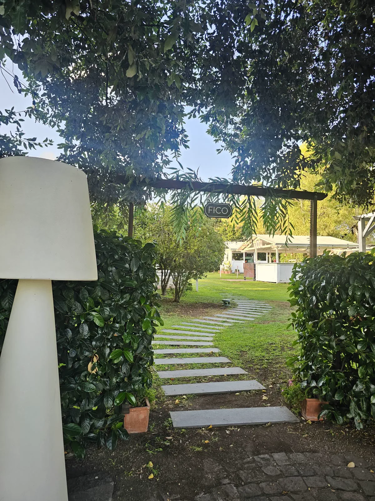 Pathway in the garden of Tenuta Villa Guerra amid greenery and pergola