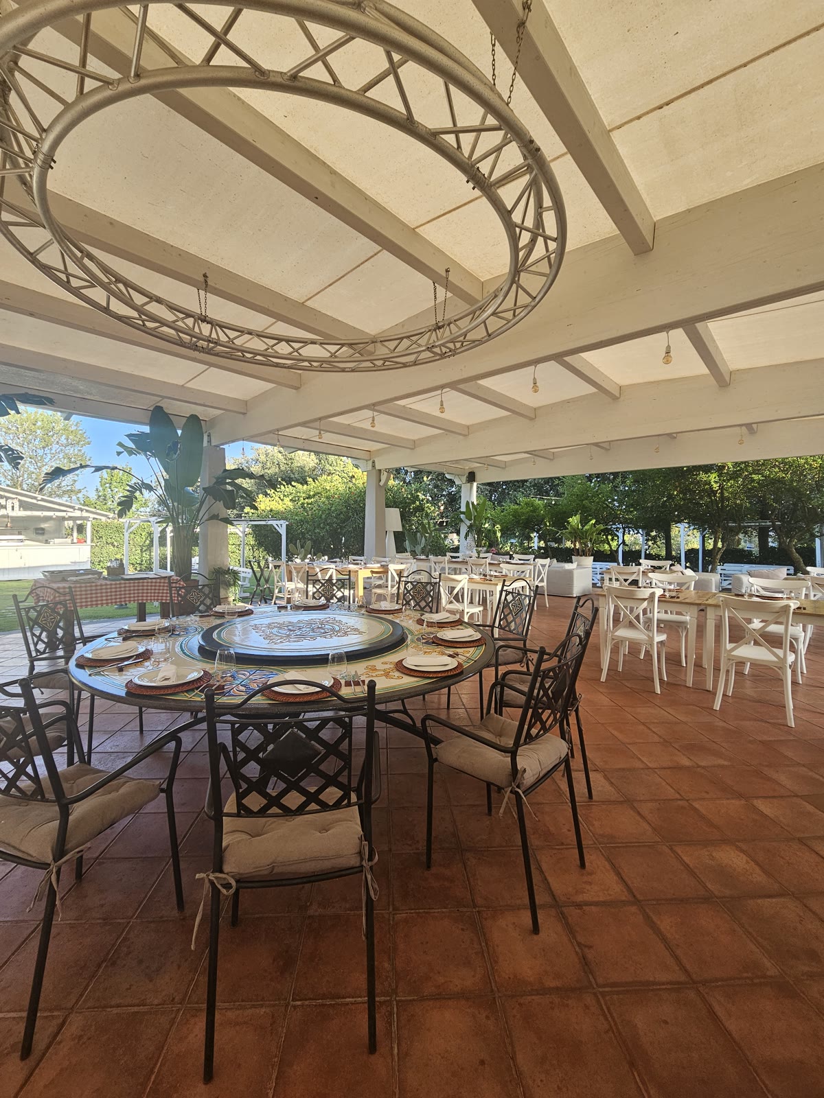 Terrazza esterna coperta della Tenuta con tavoli rotondi affacciata sul giardino